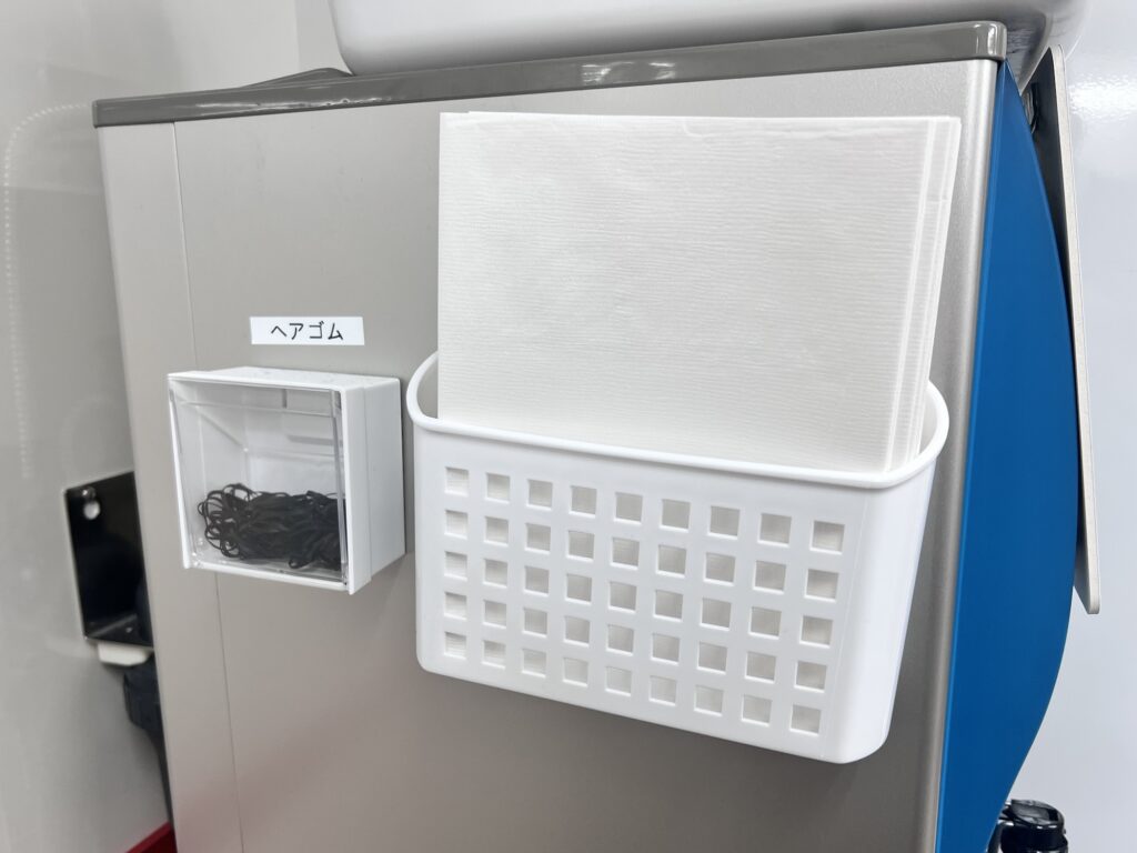 なぎちゃんラーメン冷水機横の紙エプロンとヘアゴム