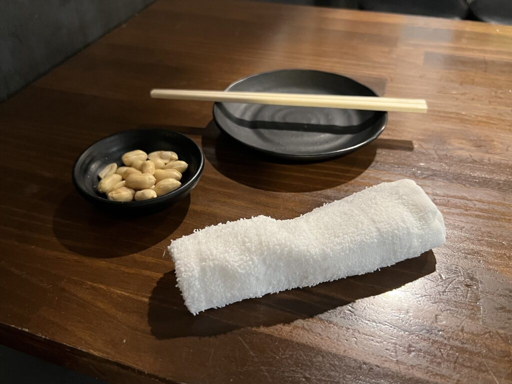 もつ焼きばん小皿、お通し、布おしぼり