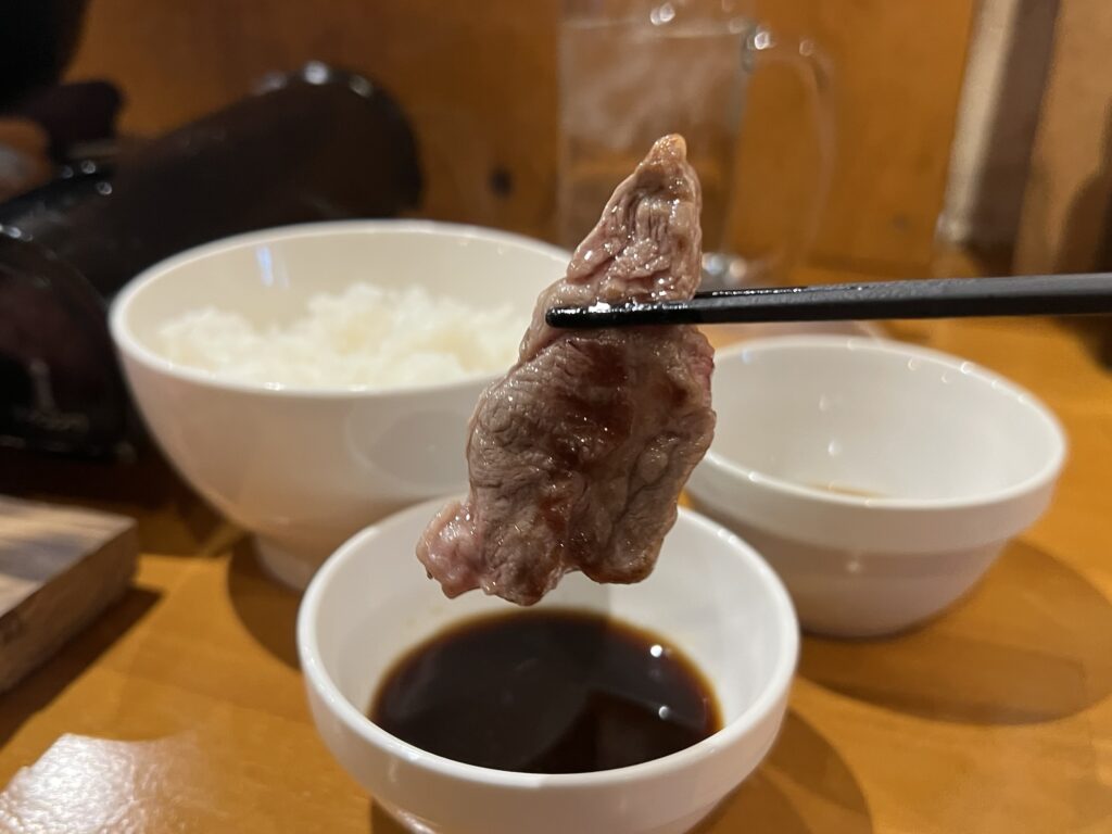 隣のロッヂ肉をタレにつけるところ